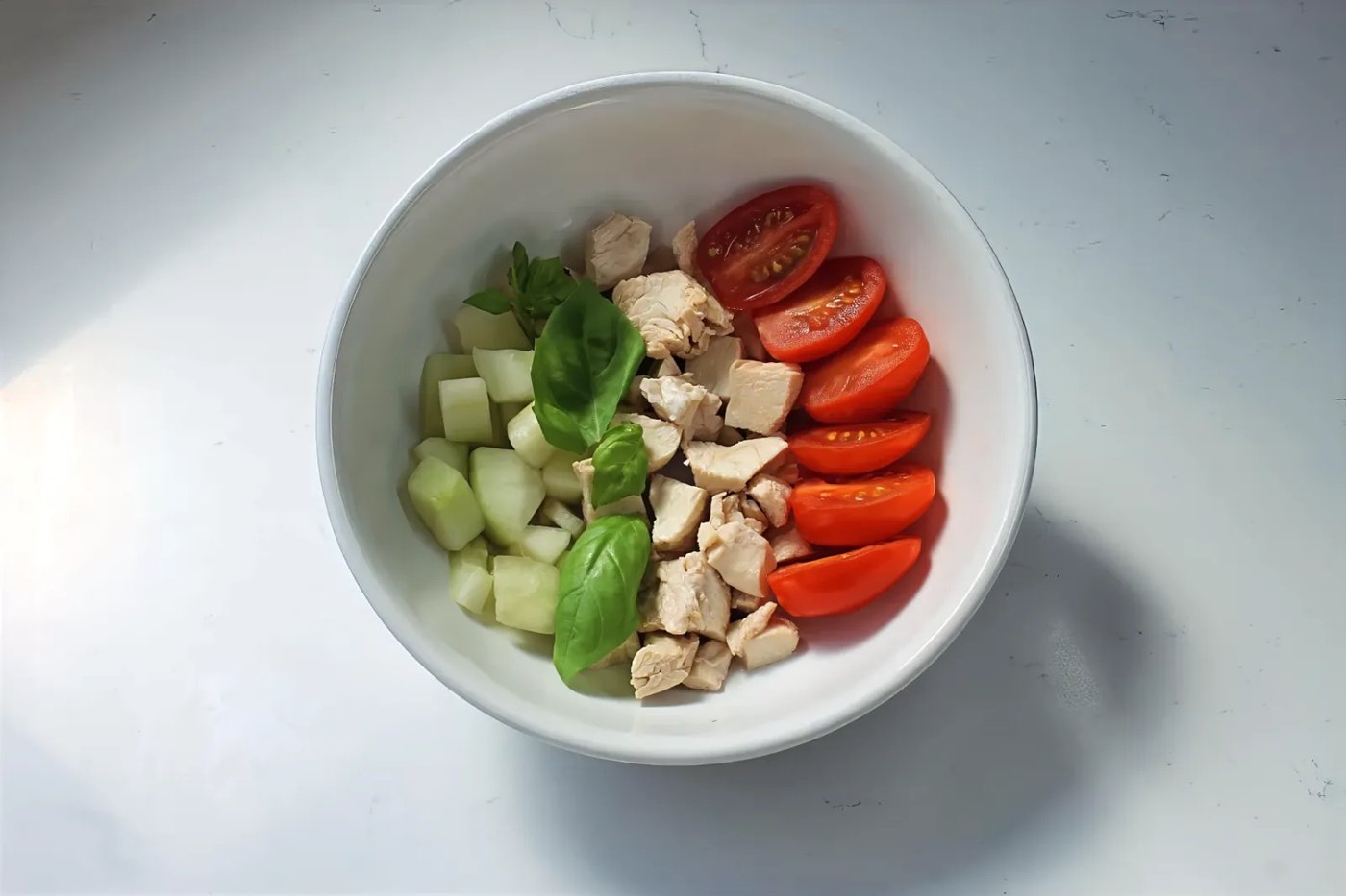 Diced chicken breast bowl with cucumber, cherry tomatoes and fresh basil